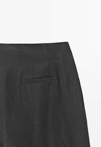 Jupe en lin noir avec une texture lisse, des coutures verticales et une poche arrière discrète. Design classique avec une silhouette droite.