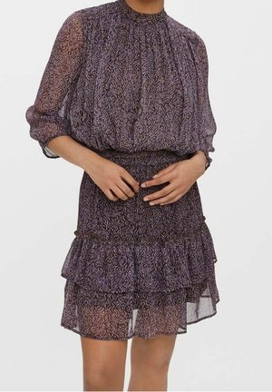 Abito viola a fantasia con maniche lunghe trasparenti, scollo arricciato e orlo a balze su più livelli. Tessuto leggero con contrasti di texture.