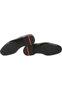 Chaussures en cuir marron avec un dessus lisse, semelles en caoutchouc noir et accents rouges à l'arrière, présentant une pointe arrondie et un minimum de détails.