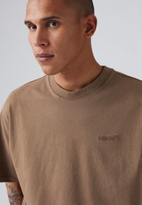 Bruine katoenen T-shirt met een ronde hals, voorzien van een ton-sur-ton geborduurd Levi's logo op de borst en korte mouwen. Soepele textuur.