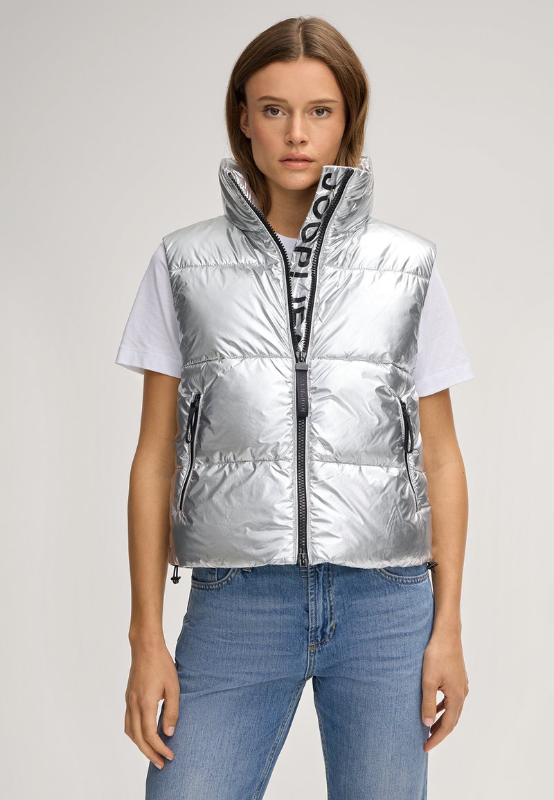 Srebrna kamizelka puchowa z wysokim kołnierzem, przednim zamkiem błyskawicznym i wyraźnym czarnym logo. Lekki, błyszczący materiał z bocznymi kieszeniami.