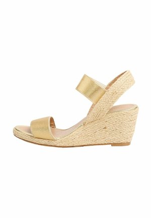 Gold wedge sandals with a textured jute sole, wide straps, and a smooth upper. Open toe design with a minimalist silhouette.