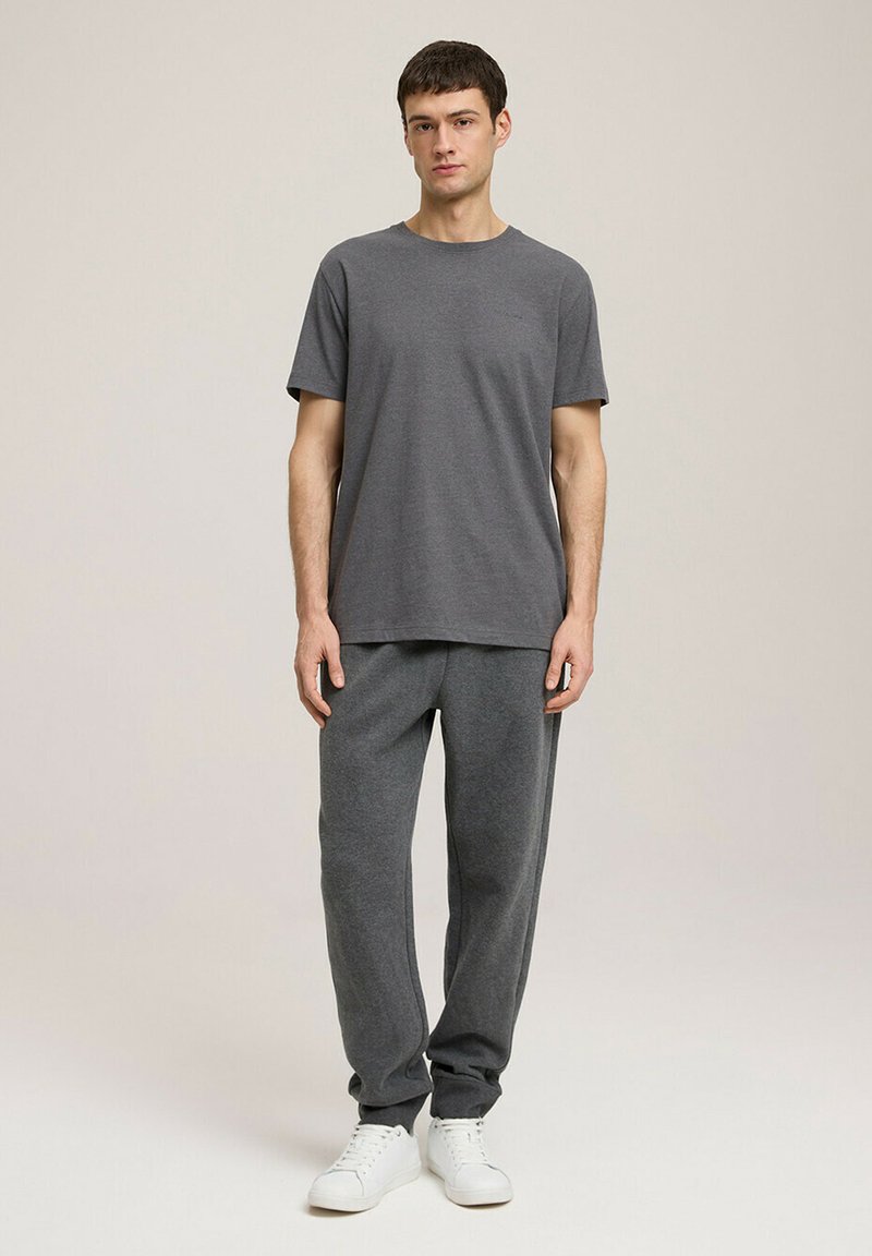 Szara bawełniana koszulka z krótkim rękawem, połączona z pasującymi szarymi spodniami dresowymi. Ubranie dopełniają białe sportowe trampki.