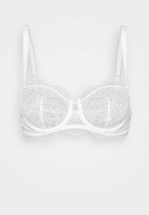 Soutien-gorge en dentelle blanche avec un design à armatures, présentant des motifs floraux détaillés, des bretelles réglables et des bords festonnés.