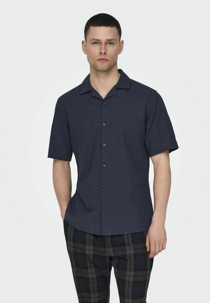 Camisa de manga corta de color azul oscuro hecha de tejido ligero, con cuello extendido, cierre de botones y un corte relajado.