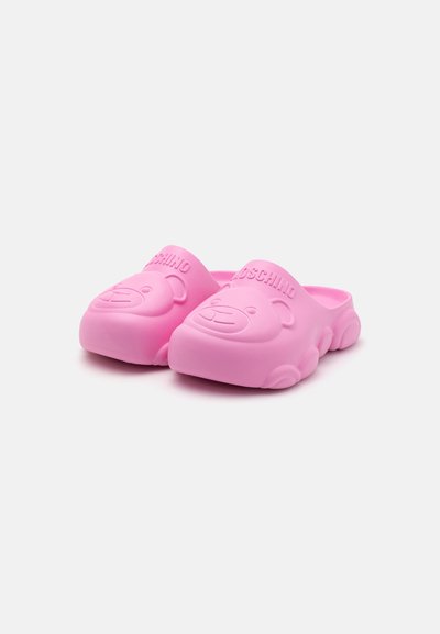 Roze silikonski klobuki imajo na sprednji strani dvignjen motiv medvedka in blagovno znamko "Moschino". Imajo gladko teksturo z zaobljenimi robovi in debelimi podplati.
