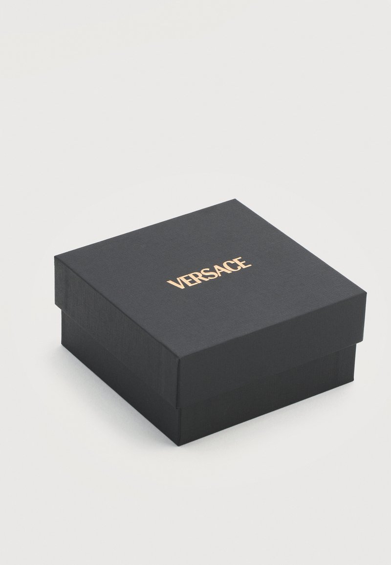 Black square luxury box with textured surface and gold "VERSACE" logo centered on the lid, set against a plain light background.