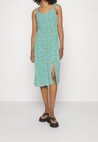 Vestido floral verde con tirantes finos, a la altura de la rodilla, con una abertura lateral, hecho de tela ligera, con escote en V y un corte relajado.