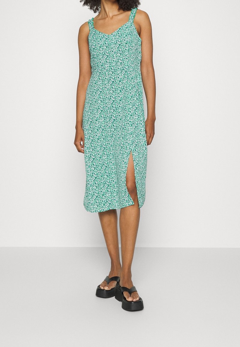 Vestido floral verde con tirantes finos, a la altura de la rodilla, con una abertura lateral, hecho de tela ligera, con escote en V y un corte relajado.