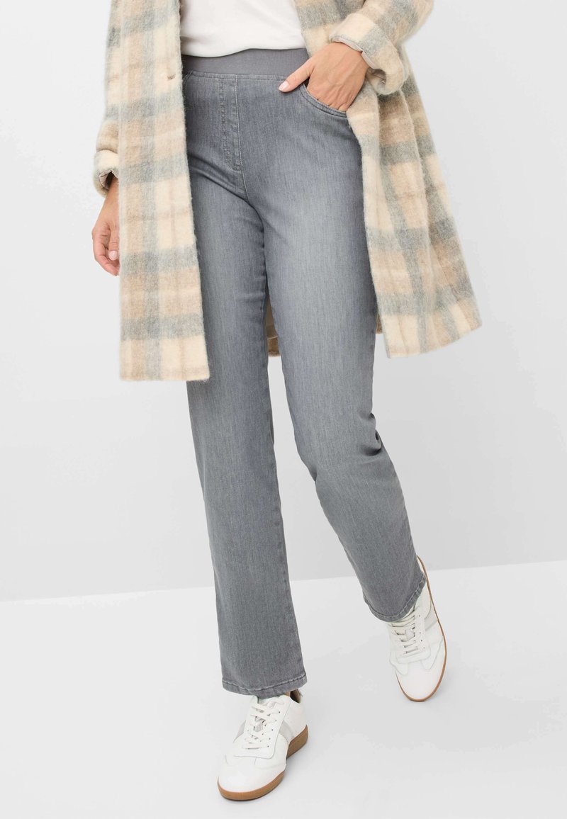 Pantalons en denim gris à jambe droite avec une texture lisse, associés à un manteau à carreaux beige et gris et des baskets blanches.