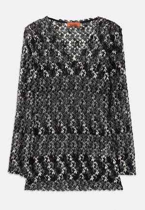 Black and white lace top featuring a V-neck, long sleeves, and a floral pattern with intricate textures and scalloped edges.