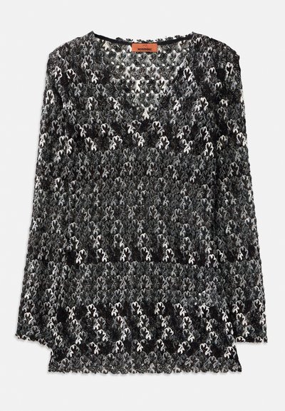 Top dantelat negru și alb, cu decolteu în V, mâneci lungi și un model floral cu texturi intricate și margini ondulate.