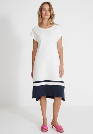 White knit dress with cap sleeves, navy bottom band, and two horizontal stripes. Paired with pink slip-on sandals.
