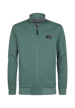Chaqueta verde con cremallera, textura acolchada en la parte superior delantera, puños y cuello acanalados. Cuenta con un parche con logo en el pecho izquierdo.