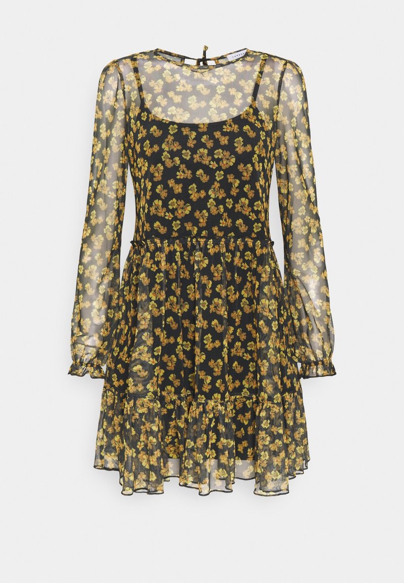Robe longue noire transparente à manches longues avec imprimé floral jaune, encolure dégagée, ourlet à volants et jupon intérieur sans manches.
