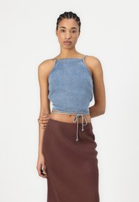 Denim cropped top with adjustable drawstring hem, featuring thin straps and a light blue color. Paired with a brown, form-fitting skirt.