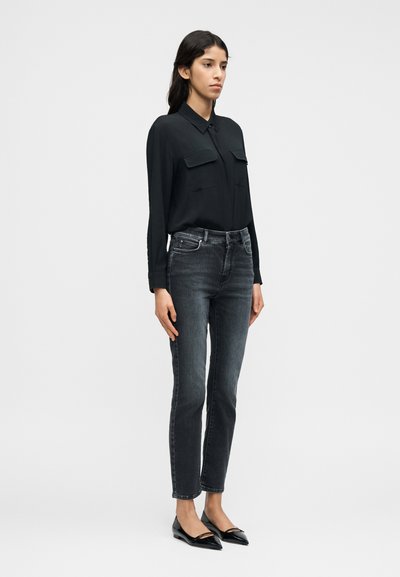 Μακρυμάνικο μαύρο πουκάμισο με δύο τσέπες στο στήθος, σε συνδυασμό με σκούρα τζιν στενής γραμμής και μαύρες μπαλαρίνες με μυτερή μύτη. Απλή, κομψή σιλουέτα.