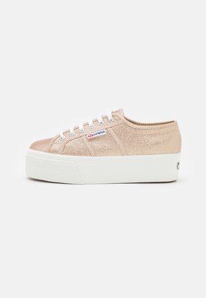 Brokatowe, różowo-złote sneakersy na platformie z białymi sznurowadłami i grubą białą podeszwą, z małym logo Superga po boku.