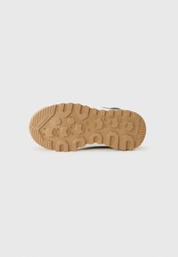 Semelle d'une chaussure avec un design texturé et robuste pour une bonne adhérence ; les couleurs comprennent du caoutchouc marron et un dessus en tissu noir contrastant.