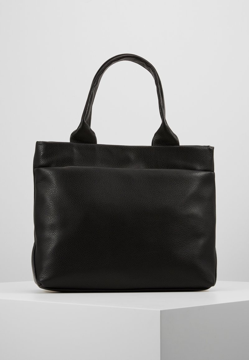 Sac cabas en cuir noir texturé avec double poignée, debout sur un piédestal blanc sur un fond gris clair uni.