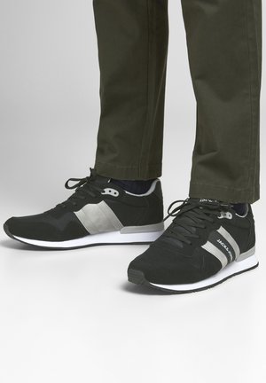 Sneaker sportive nere con strisce laterali grigie, tomaia in tessuto testurizzato, design con lacci e suola bianca.