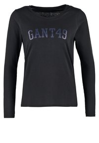 Pitkähihaisen mustan puuvillapaidan, jossa on pyöreä kaula-aukko ja "GANT49" -logo tummanharmaana rinnan kohdalla. Pehmeä ja sileä tekstiili.