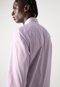 Camisa de botones a rayas morado claro y blanca con cuello clásico, mangas largas y una textura suave, que muestra detalles de costura.