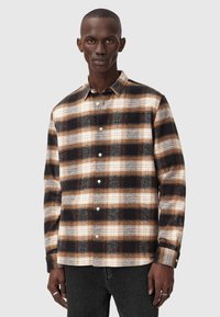 Långärmad rutskjorta i svart, brunt och krämfärgat, med krage med knappar och bröstficka, tillverkad av fleece.