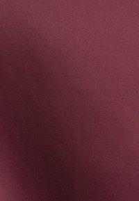 Bordeaux stof met een gladde textuur en subtiel ribbelpatroon, geschikt voor kleding of stoffering. Rijke, diepe kleur met een uniforme afwerking.