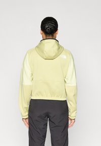 Jachetă verde deschis cu glugă, cu panouri laterale texturate, tiv elastic și accente cu logo. Proiectată pentru confort, cu o croială ușor scurtată.