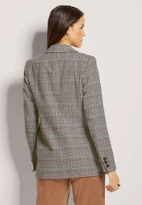 Grau kariertes Blazer mit schwarzen und roten Akzenten. Verfügt über einen Reverskragen, strukturierte Schultern und Knopfdetails an den Manschetten.