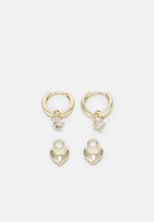 Boucles d'oreilles créoles en or avec des breloques en pierres précieuses transparentes et deux breloques en forme de cœur en or séparées sur fond blanc.