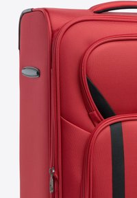 Rode stoffen koffer met een gestructureerd oppervlak, voorzien van een zwarte accentstreep, een ritsvak en een zijhandgreep voor gemakkelijk dragen.