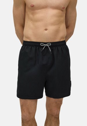 Bañador negro con cintura elástica, que presenta un cordón de ajuste en contraste blanco y negro, fabricado en una tela suave y sin patrones visibles.