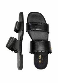 Czarne skórzane sandały z falbaniastymi paskami i płaską podeszwą. Ozdobione złotym logo marki na wkładce. Prosty i otwarty design ułatwiający zakładanie.