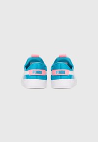 Une paire de baskets Puma turquoise et blanche avec des pattes de tirage roses et le logo Puma à l'arrière, montrées de l'arrière sur un fond blanc.