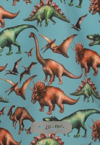 Des motifs de dinosaures colorés sur un fond bleu clair présentant différentes espèces, y compris un Tricératops et un stégosaure. Logo du fabricant visible.