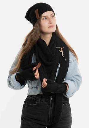 Duo bonnet en tricot noir et écharpe, associé à des gants sans doigts noirs. L'écharpe présente une texture tissée ; le bonnet a un design côtelé.