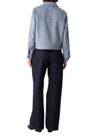 Jasnoniebieska krótka kurtka z miękkiego materiału z kołnierzem i zapięciem na guziki, zestawiona z ciemnoniebieskimi spódnicami dzwonami.