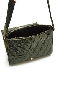 Borsa a tracolla trapuntata verde oliva con chiusura a zip, tracolla regolabile e un accento hardware color rosa pallido a contrasto. Superficie testurizzata.