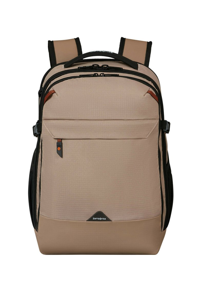 Zaino in tessuto beige con dettagli neri, multiple cerniere e una tasca frontale. Presenta spallacci imbottiti e una superficie testurizzata.