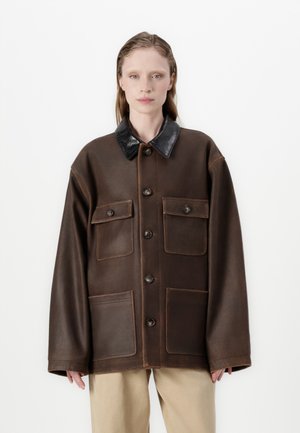 Chaqueta de cuero marrón con un collar negro brillante, dos bolsillos en el pecho y dos bolsillos inferiores. Presenta grandes botones y un ajuste relajado.