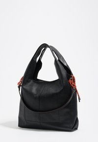 Czarna skórzana torba o miękkiej fakturze, w stylu hobo, z pojedynczym paskiem na ramię i czerwonymi ozdobami przy uchwytach.