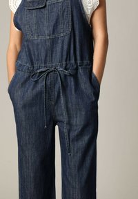 Denim tuinbroek met een donkerblauwe wassing, elastische tailleband met een trekkoord, voorzak en brede pijpen met een relaxte pasvorm.