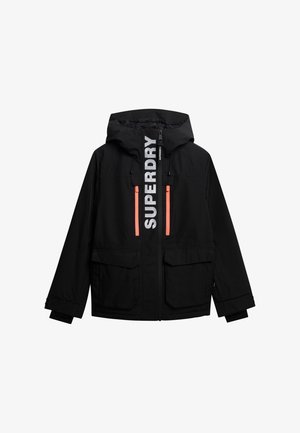 Schwarze wasserdichte Jacke mit Kapuze, die ein auffälliges weißes "SUPERDRY"-Logo und neongelbe Reißverschlusstaschen aufweist. Mit zwei großen Fronttaschen.