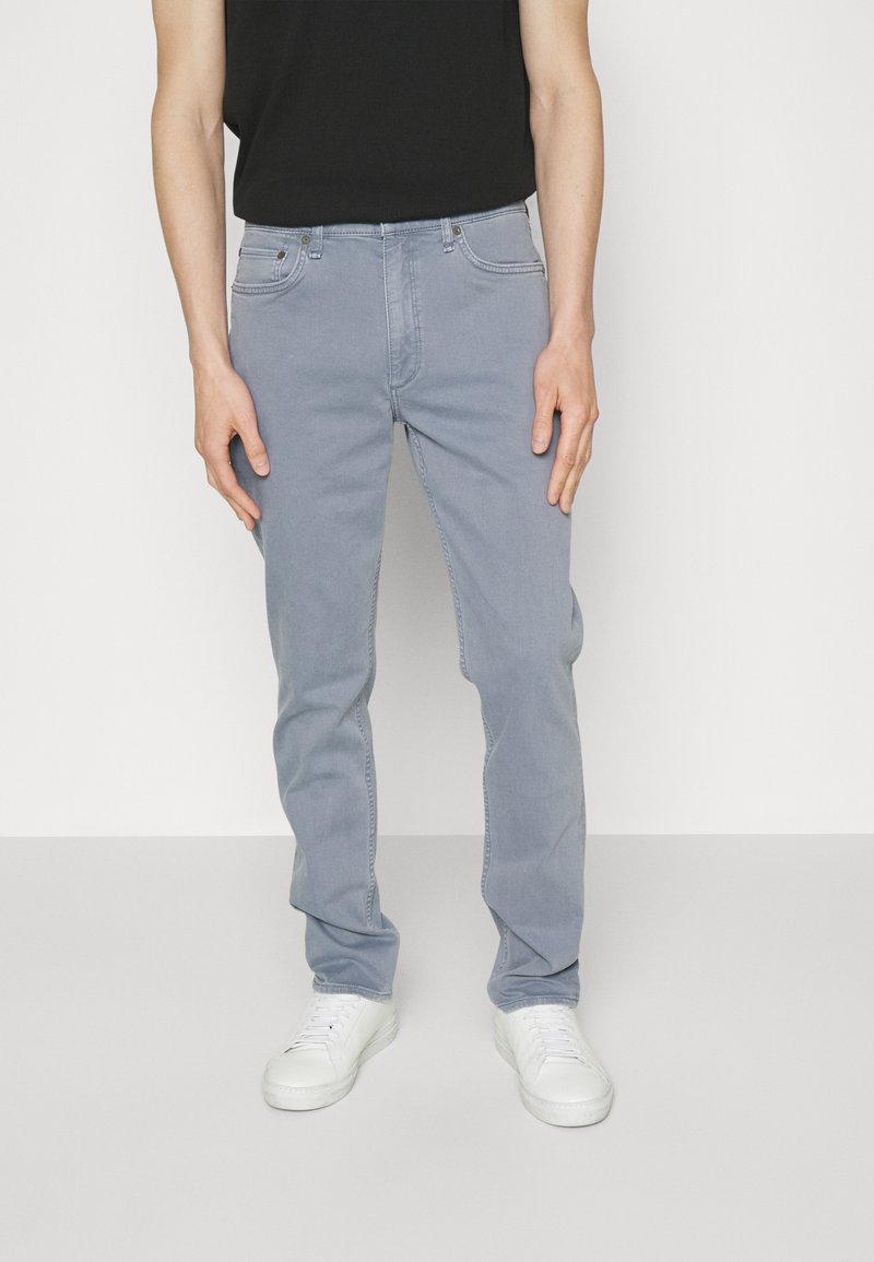 Light gray jeans with a straight-leg design, made of denim. Features front pockets and a subtle texture, paired with white sneakers.