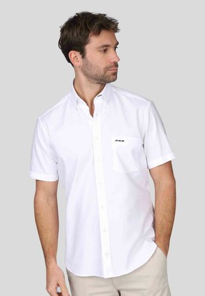 Chemise blanche à manches courtes, en tissu lisse. Elle présente une poche poitrine avec un petit logo noir, un col classique et une coupe décontractée.