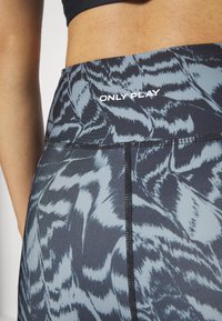 Legginsy o wysokim stanie z czarno-szarym abstrakcyjnym wzorem, gładką teksturą i wykończeniem szytym. Logo „ONLY PLAY” w białym kolorze na pasa.