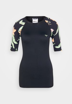 Black rash guard with short, patterned sleeves featuring tropical flowers and leaves. Roxy logo on the chest. Stretchy, fitted design.