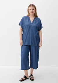 Denim top with a V-neck and short batwing sleeves, paired with wide-leg denim pants. Both in a consistent blue color, featuring subtle stitching.